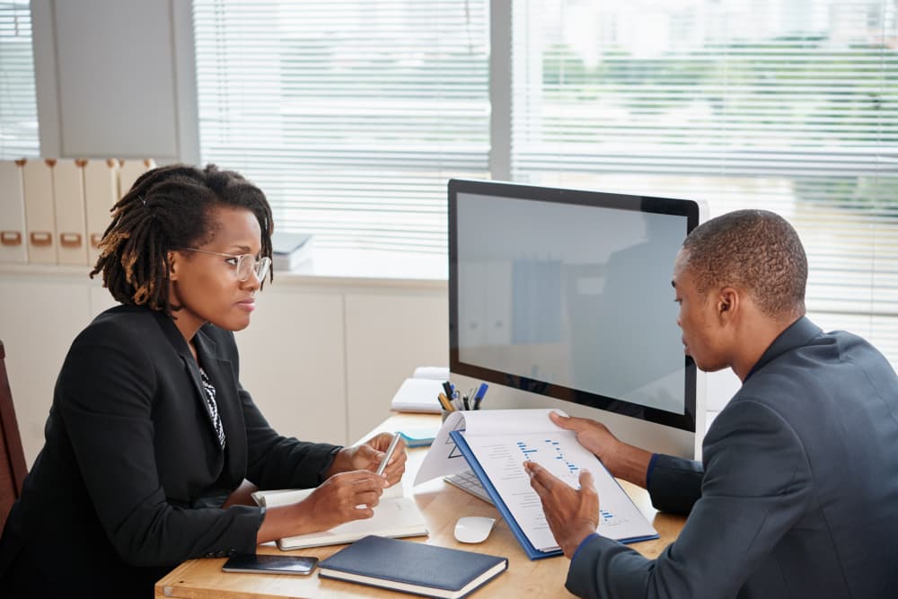 African gent and lady officially dressed in an office as the gent explains some documents he's holding | Netsheria company secretarial services to SMEs and start ups